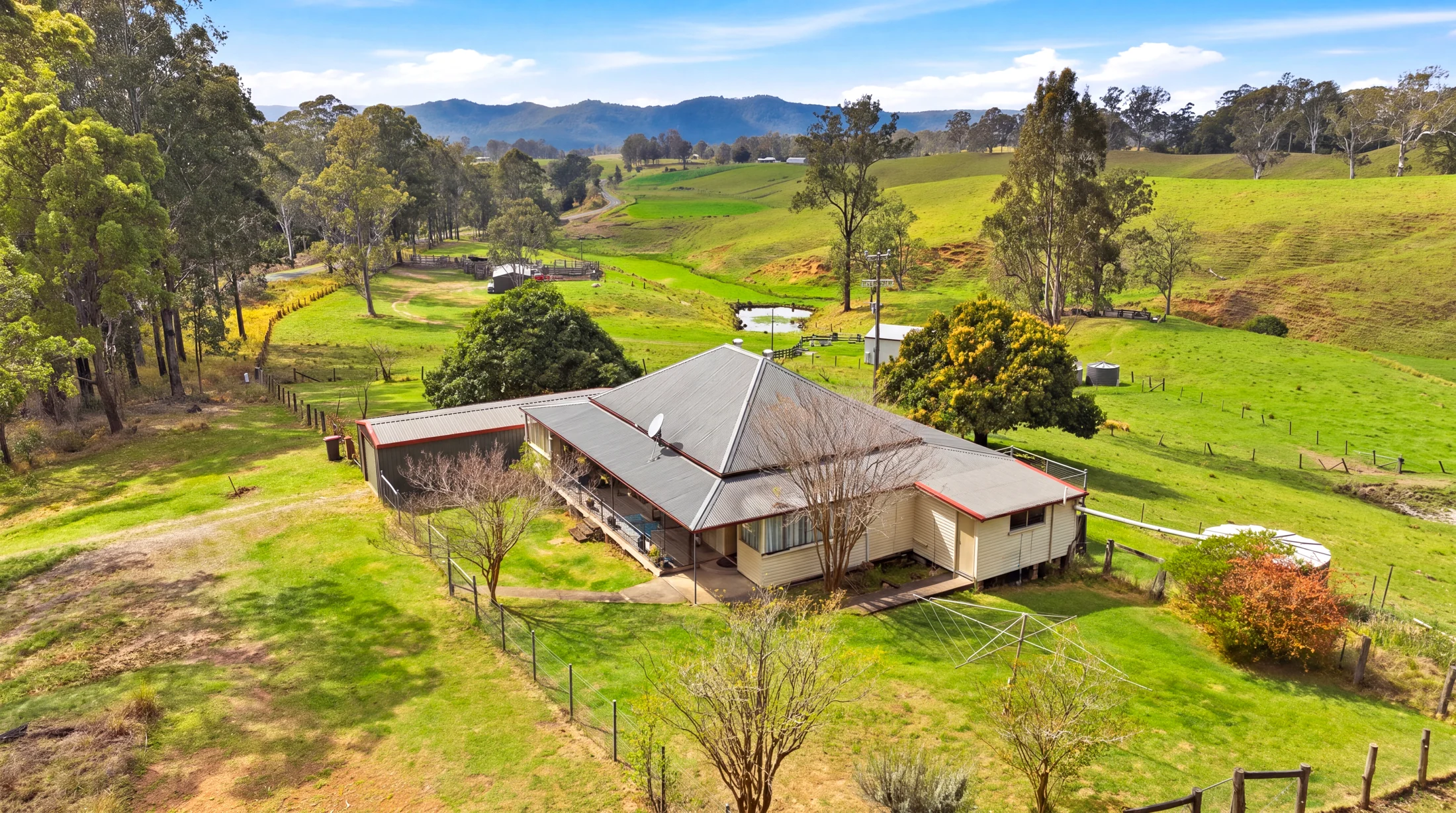 Aerial view of the homestead, shed and surrounding green paddocks