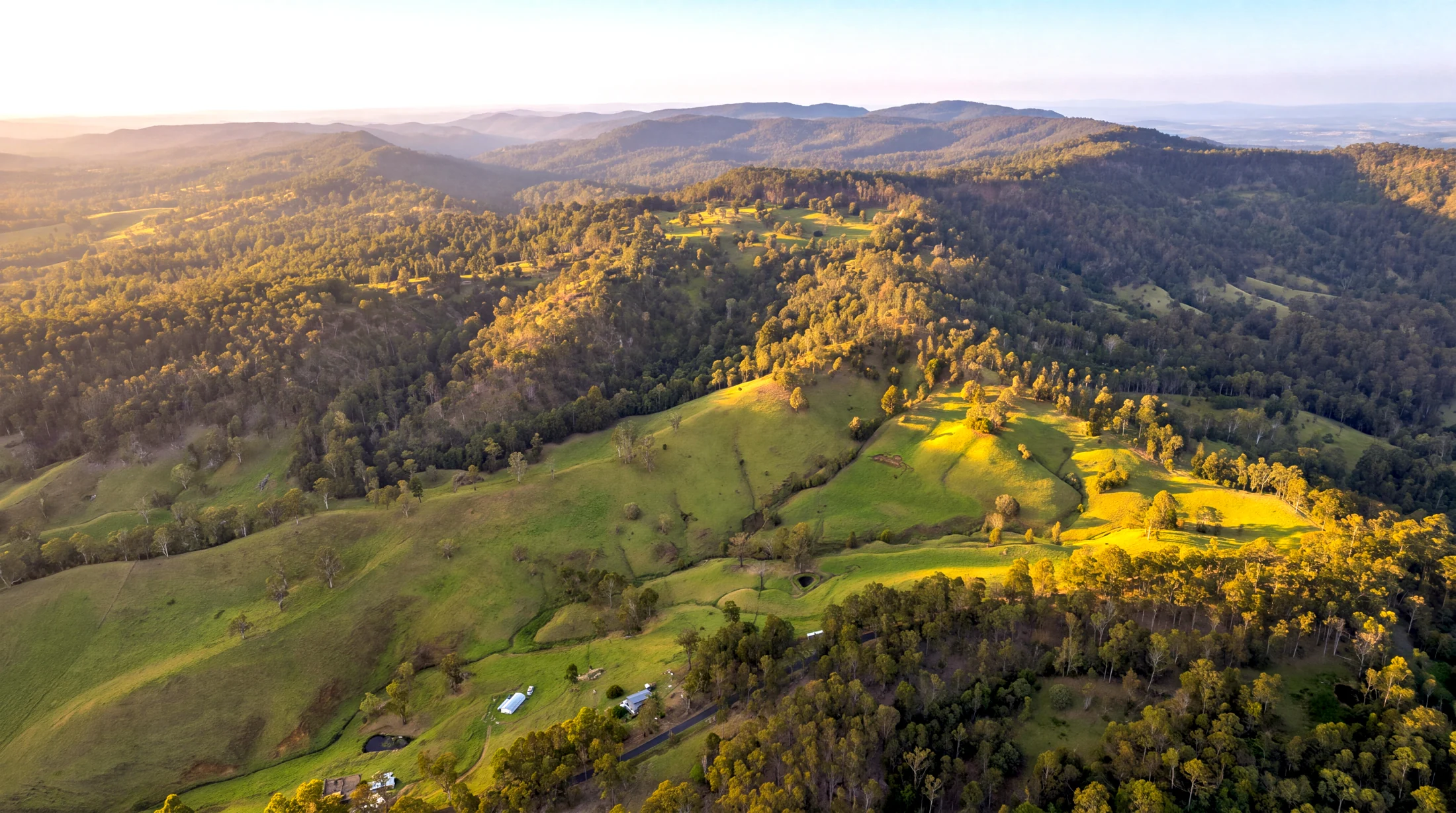 Sweeping valley views across open pasture and native woodland